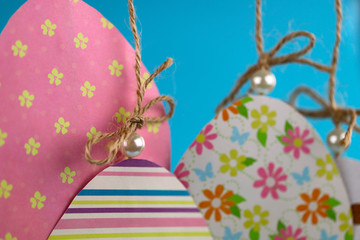 Easter background handmade. Group of colored eggs made of paper hang on a rope on a blue background. Cropped shot, close-up, nobody, horizontal. Easter concept.