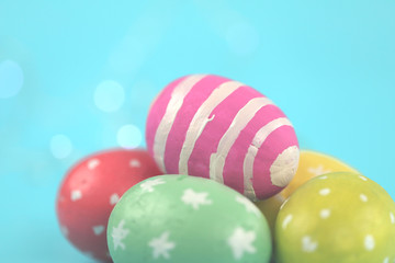 Easter background. Green, red and yellow painted eggs handmade on a blue background with bokeh. Cropped shot, close-up, nobody, horizontal, blurred, free space. Easter concept.