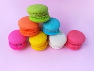 Fototapeta na wymiar Delicious macaron place the shape like a pyramid on pink background, colorful macaroon arranged in layers