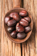 close up of dried jojoba seeds in the wooden spoon, on the wooden table