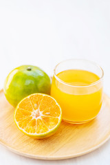 Green tangerine orange fruit and juice on wooden plate