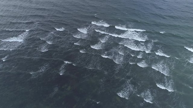 Waves breaking in dark blue sea aerial view