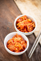 Kimchi cabbage in a bowl with chopsticks for eating on wooden table, Korean food
