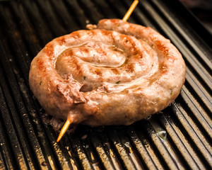 Fried spiral sausages on an electric barbecue BBQ grill. Homemade menu.