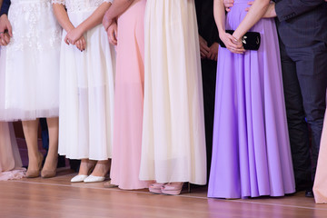 Kind of women's legs in stylish shoes and beautiful ball gowns on the background.