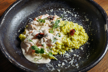  Risotto with porcini mushrooms, sauce, sun-dried tomatoes and pea sprouts on a beautiful clay deep dish of gray color