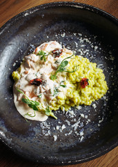  Risotto with porcini mushrooms, sauce, sun-dried tomatoes and pea sprouts on a beautiful clay deep dish of gray color