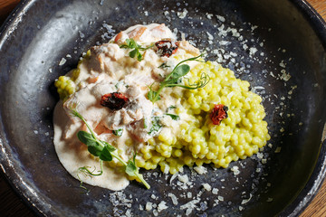  Risotto with porcini mushrooms, sauce, sun-dried tomatoes and pea sprouts on a beautiful clay deep dish of gray color