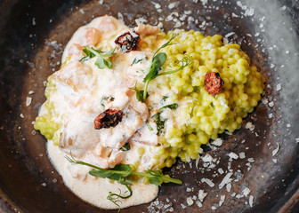  Risotto with porcini mushrooms, sauce, sun-dried tomatoes and pea sprouts on a beautiful clay deep dish of gray color