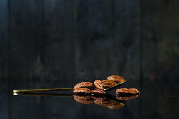 pecan nut in spoon on black background, side view