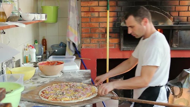 Pizza Chef Putting Large Family Pizza into Wood Burning Oven