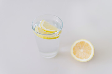 A glass of fresh cool water with lemon slices on a white background