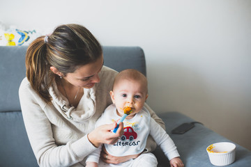 Mother, feeding her baby boy with mashed pumpking