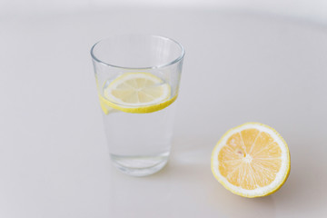 A glass of fresh cool water with lemon slices on a white background