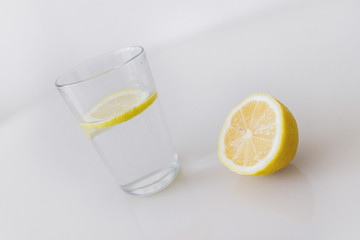 A glass of fresh cool water with lemon slices on a white background