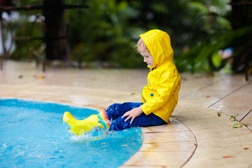Kid in swimming pool in rain. Tropical storm.