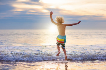 Fototapeta premium Child playing on ocean beach. Kid at sunset sea.