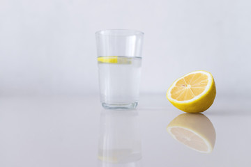 A glass of fresh cool water with lemon slices on a white background