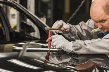 Obraz premium Employee car body painting shop eliminates a small metal defect