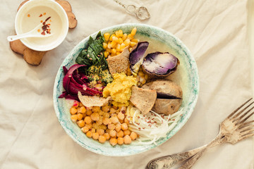 Vegan detox lunch with a purple potato, stewed spinach, and hummus with corn crackers.