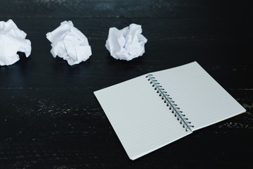 set of scrunched paper balls and empty notepad on dark moody background