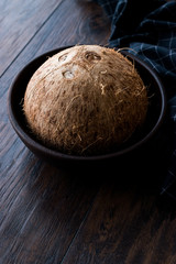 Fresh Organic Brown Raw Coconut in Dark Wooden Bowl.