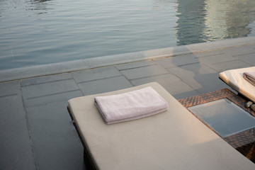 Grey Towel on relaxing pool bed beside swimming pool.