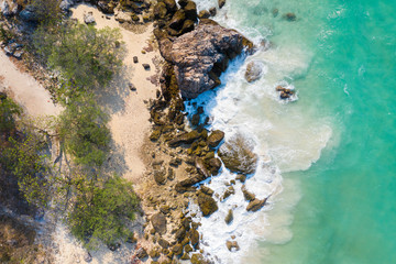 Aerial top view of ocean waves, beach and rocky coastline and beautiful forest. Beautiful nature background.
