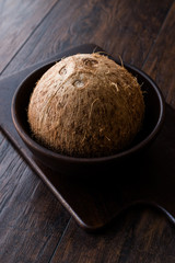 Fresh Organic Brown Raw Coconut in Dark Wooden Bowl.