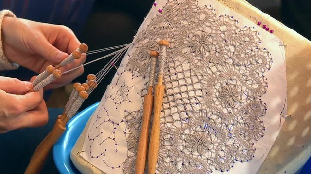 The village craftswoman spins a beautiful lace pattern from thin silk threads.
