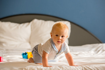Adorable baby boy, sweet child, playing in bed with colorful toy