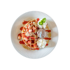 Top view of whole wheat Belgium waffle topped with strawberry syrup , whipped cream , walnuts and chocolate ice cream isolated on white background