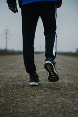 Fototapeta na wymiar Feet of a running man in pants and sneakers