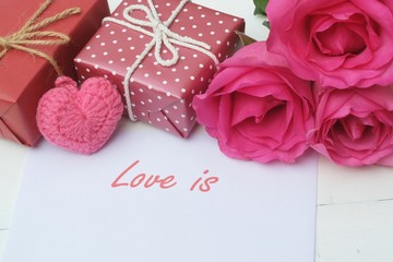 Elegant pink rose, gift box decorated with petals and card with natural soft light on wood background, beautiful valentine's day background concept