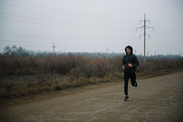 A man runs in headphones on the road. Stroke in pants and sneakers