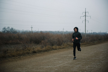 Obraz premium A man runs in headphones on the road. Stroke in pants and sneakers