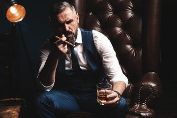 Attractive man with cigar and a glass whiskey - obrazy, fototapety, plakaty
