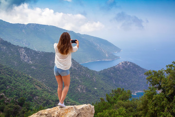 A young girl photographs the landscape on a mobile phone camera