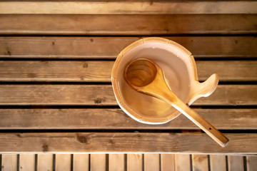 Detail of bucket and wood spoon on a wooden bench. Small interior sauna.