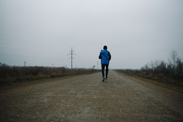 Obraz premium A man runs in headphones on the road. Stroke in pants and sneakers