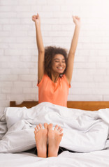 Woman stretching happily in bed after waking up