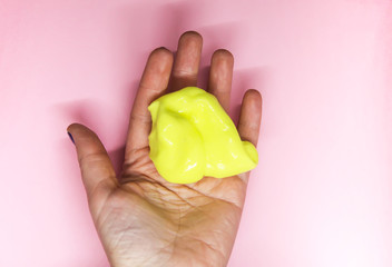 Girl playing with yellow slime in her hands.