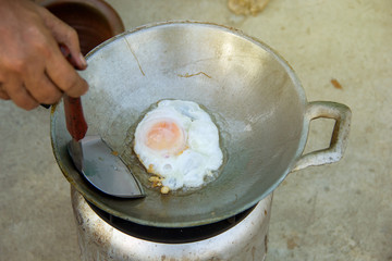 Fried egg in oil pan on biomass cooking stove. fuel used wood waste. in picnic and camping.
