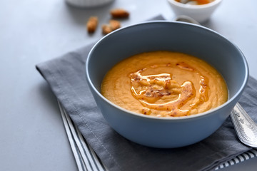 Bowl of red lentil soup on gray wooden background. Vegetarian food concept