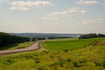 landscape with road in green field and blue sky