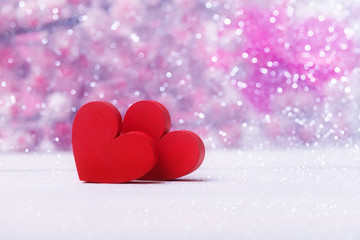 Two bright red hearts over defocused pink abstract background
