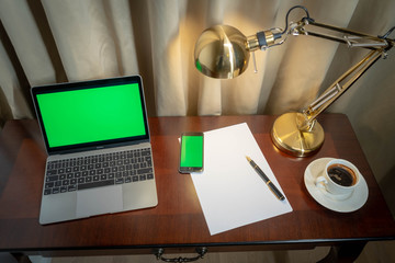 Home office notebook and cellphone with green screen