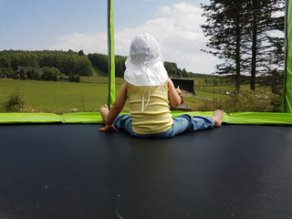 Kind sitzt im Trampolin und schaut dem Traktor zu © Andy