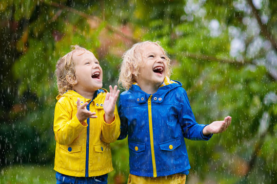 Kids play in autumn rain. Child on rainy day.