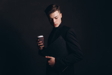 Young handsome businessman in classic black jacket and white shirt. It is time for coffee break! Handsome young man holding coffee cup